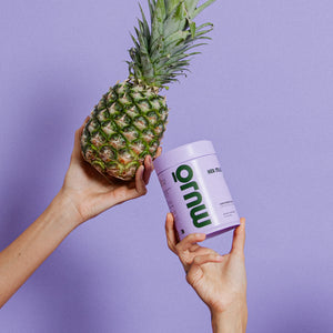 Person holding a pineapple and a MUJO Jar against a purple background